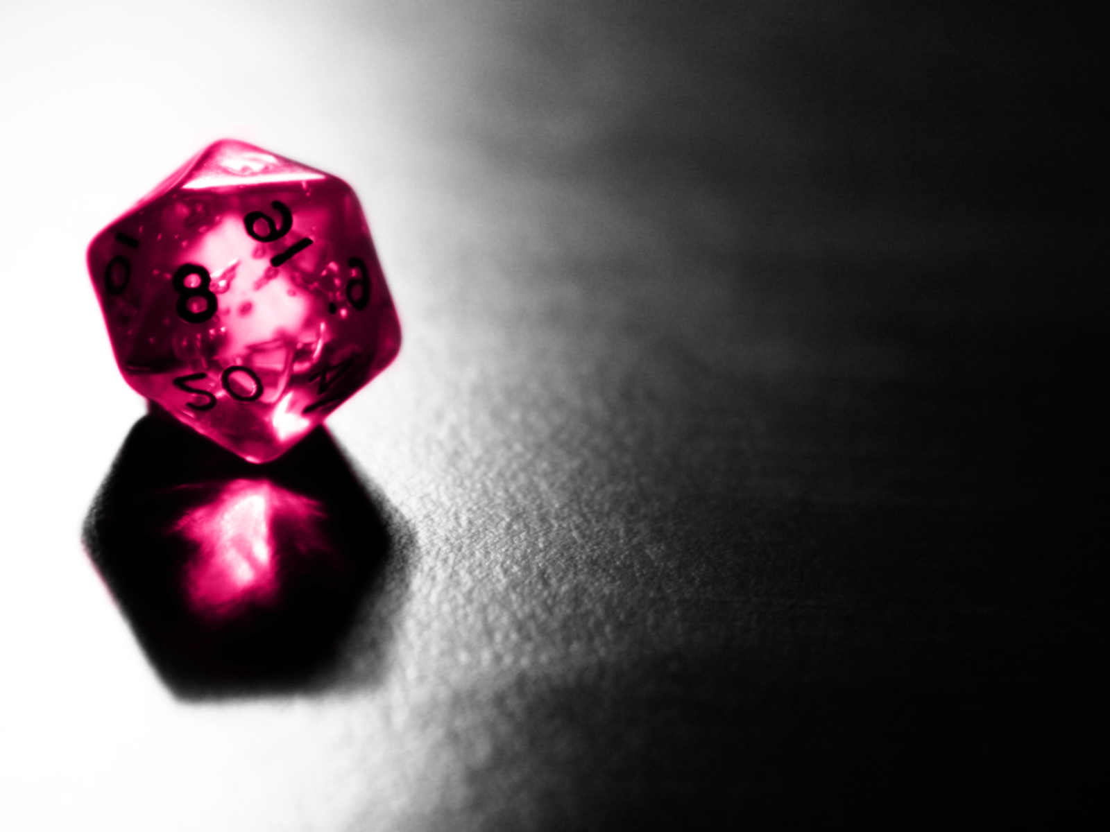 Розовый фигурный кубик отражается серой поверхности стола