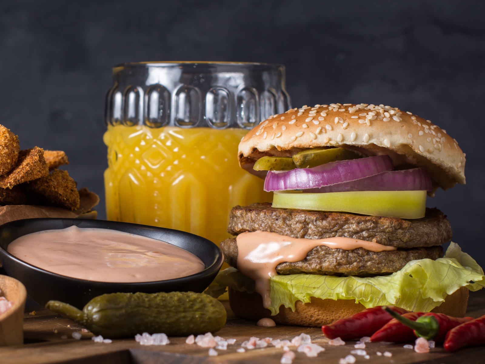Аппетитный гамбургер на столе с соусом, овощами и соком