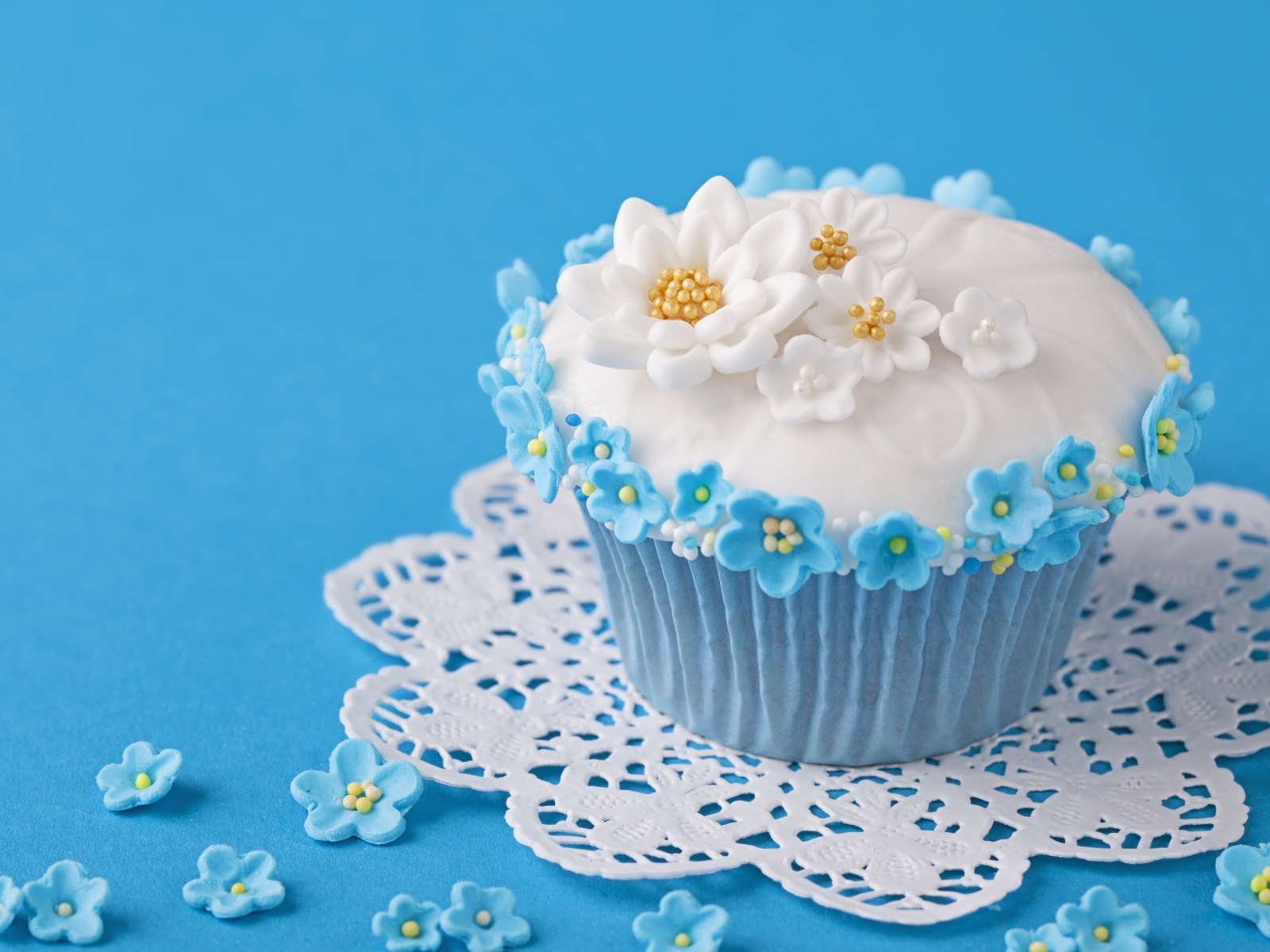 Аппетитный кекс украшен цветами на голубом фоне