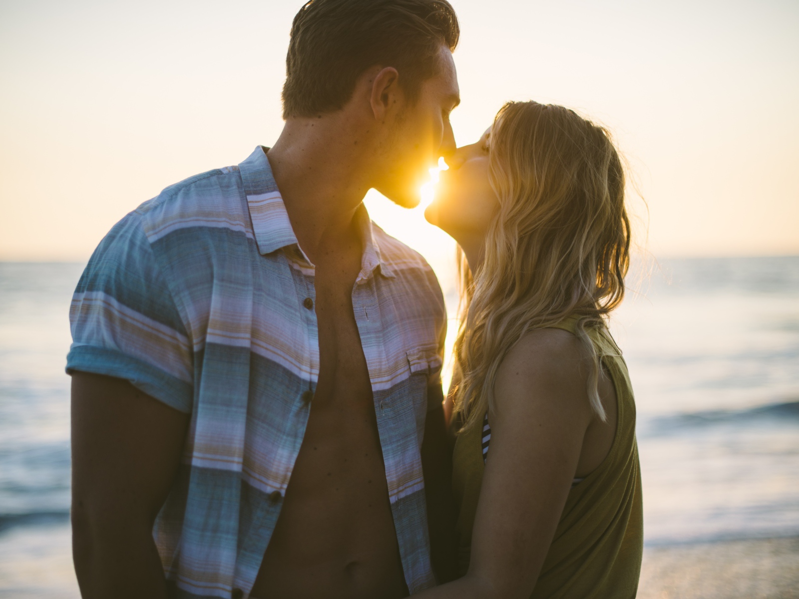 Романтический поцелуй влюбленной пары на закате солнца