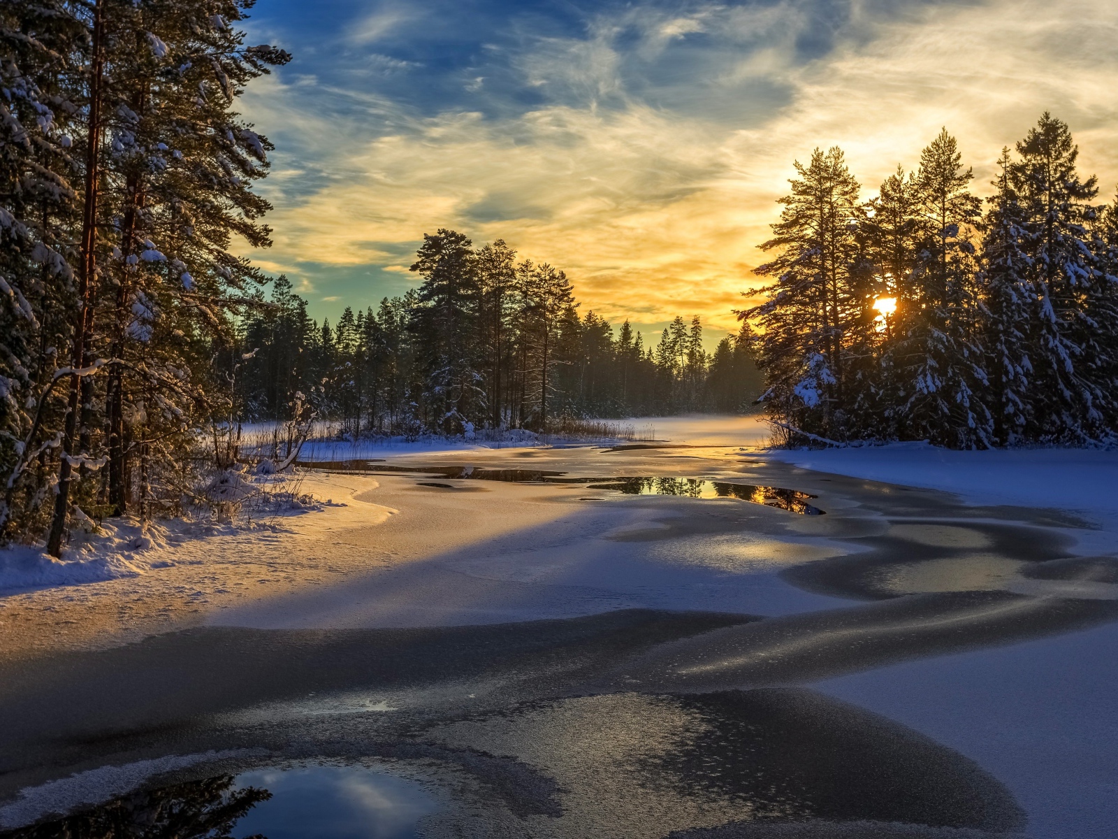Покрытая льдом река с заснеженными елями по берегам на рассвете