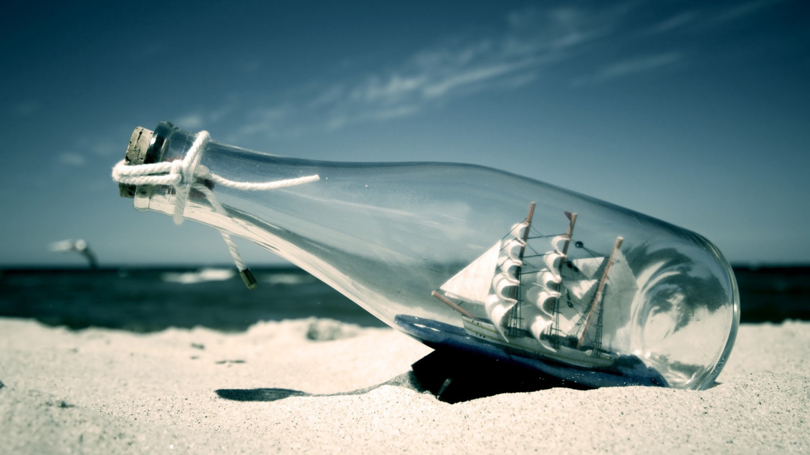 Фигурка корабля в бутылке на пляже