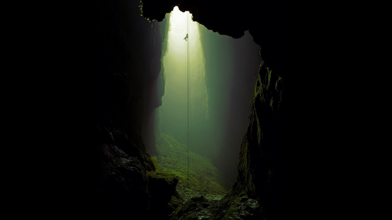 Спелеолог спускается по канату в пещеру