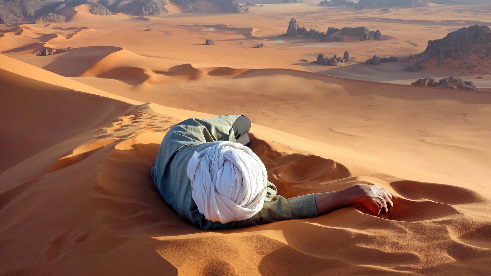 Человек лежит на песке в пустыне