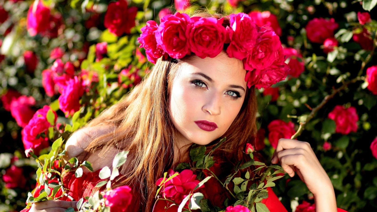 Красивая девушка с венком из красных роз на голове 