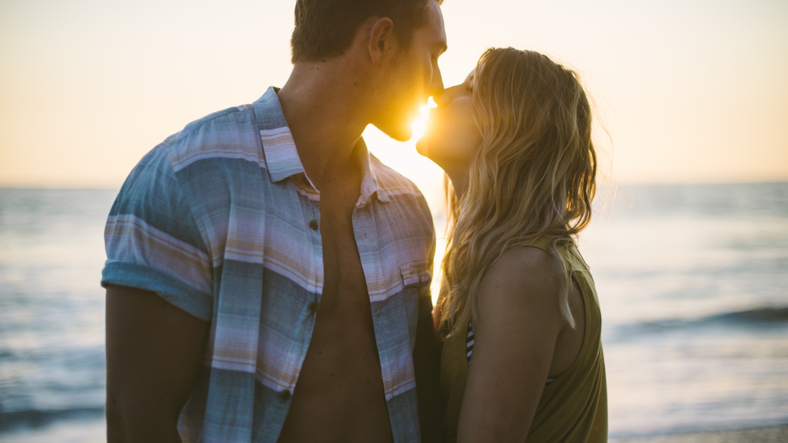 Романтический поцелуй влюбленной пары на закате солнца