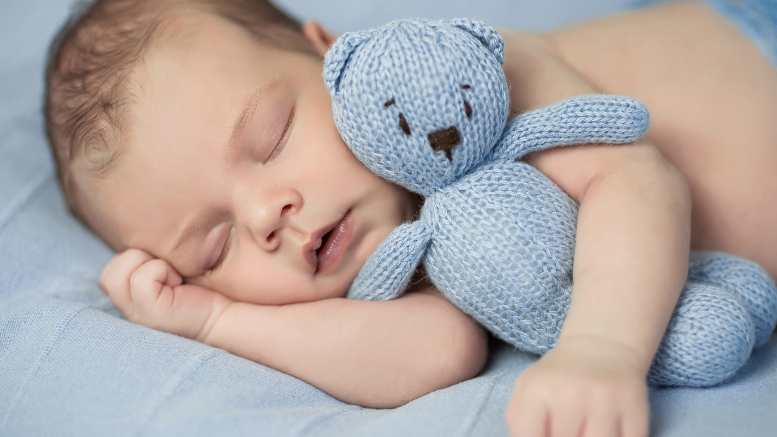 Милый спящий младенец с вязаной мягкой игрушкой