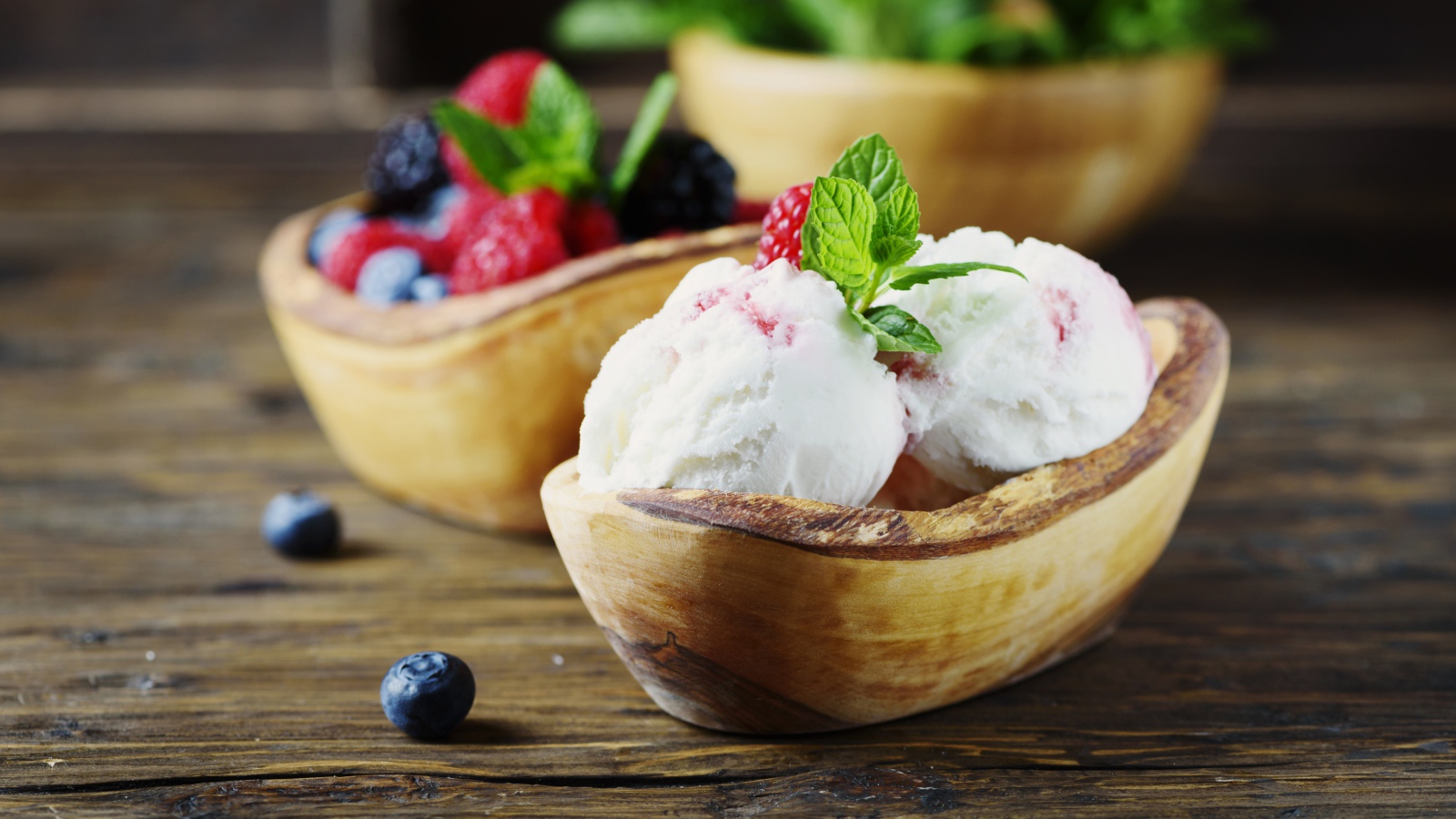 Ice cream balls with berries in a wooden bowl