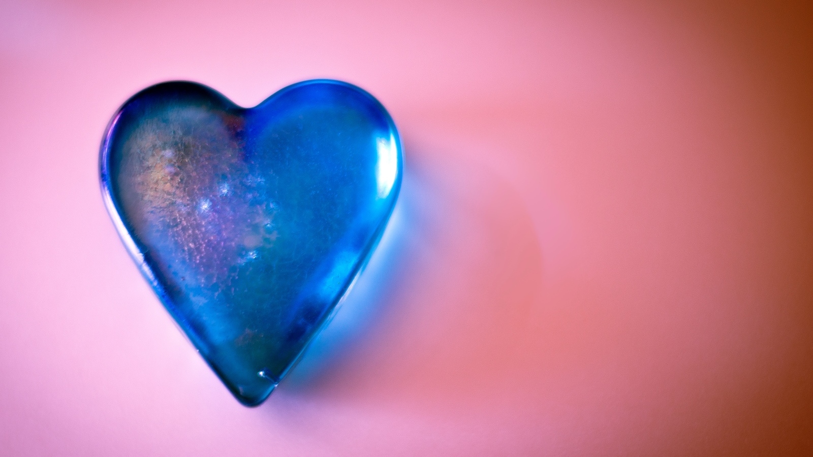 Синее стеклянное сердце на розовом столе