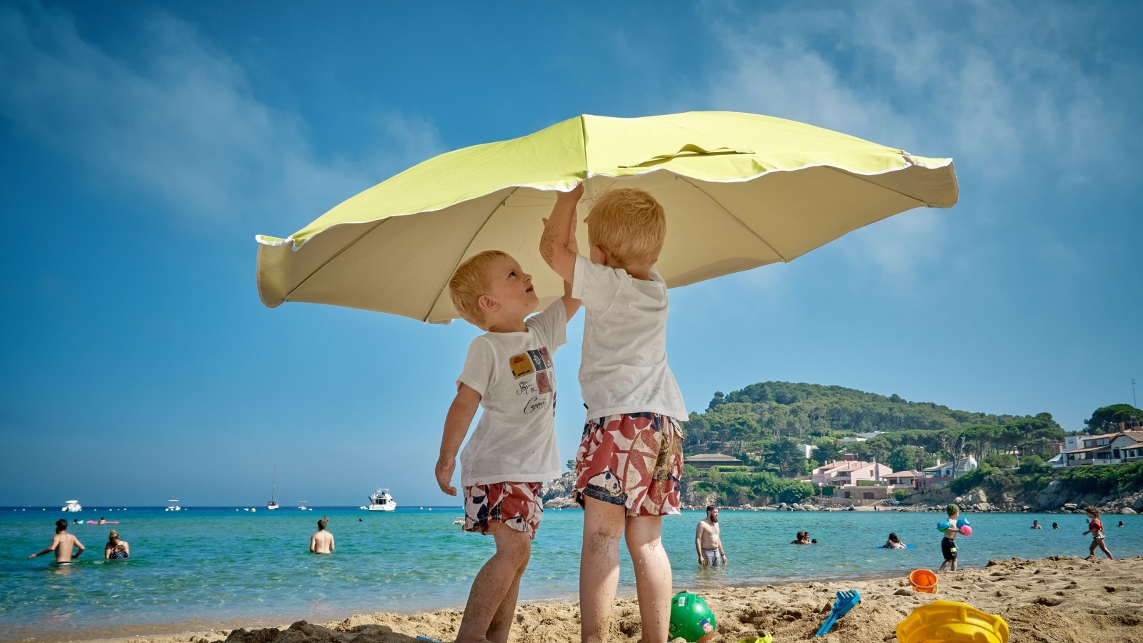 Два мальчика на пляже под зонтом