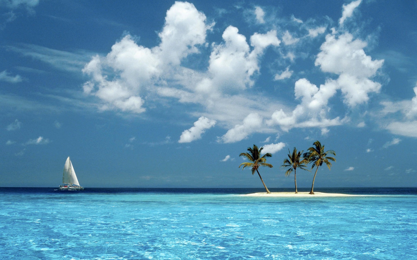 Парусник у песчаного острова с пальмами