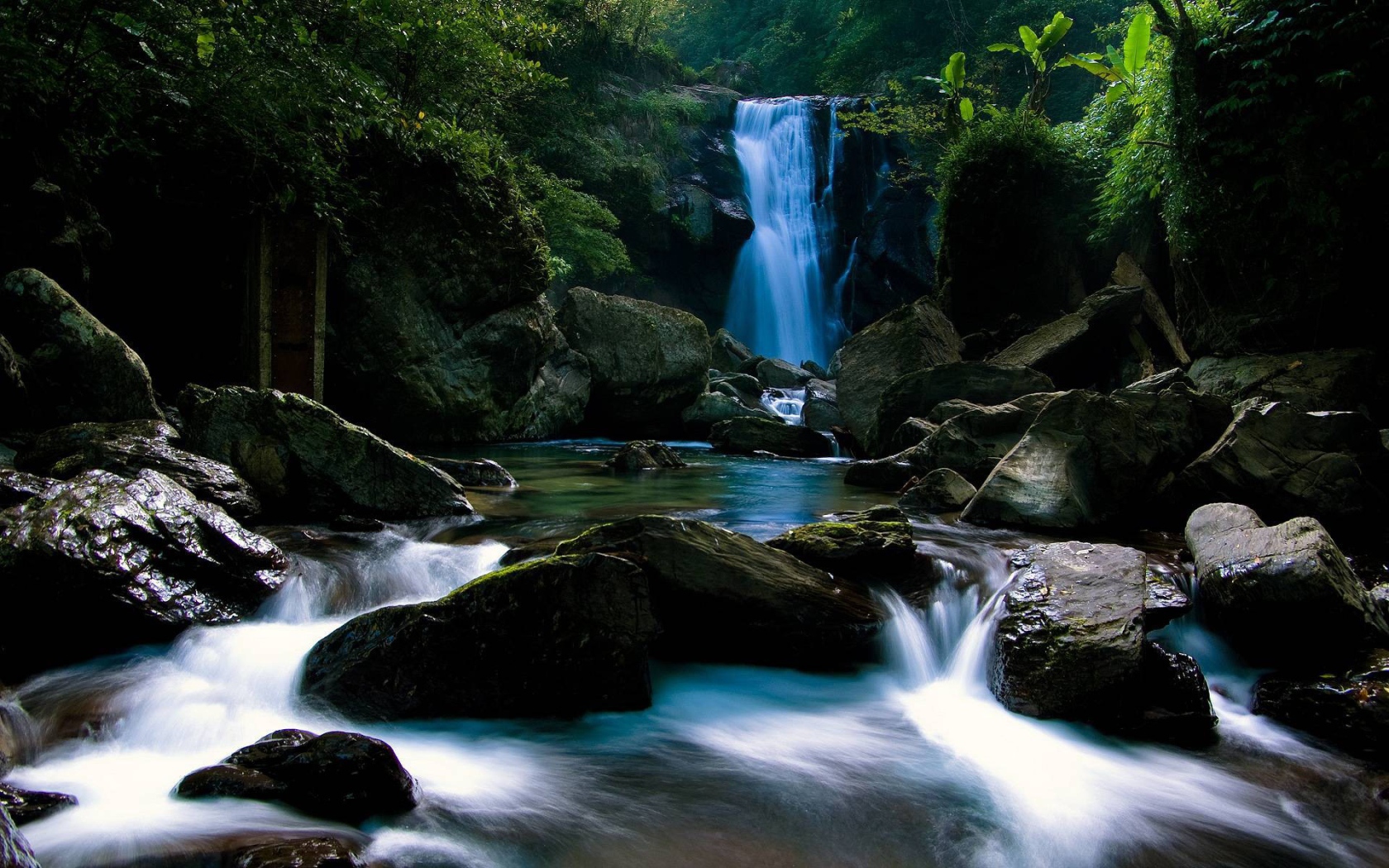 Голубой водопад позади камней на реке