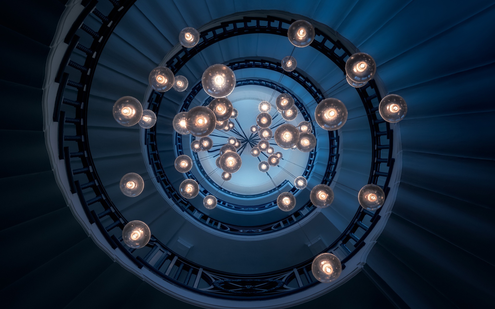Большая люстра с висячими лампочками над лестницей