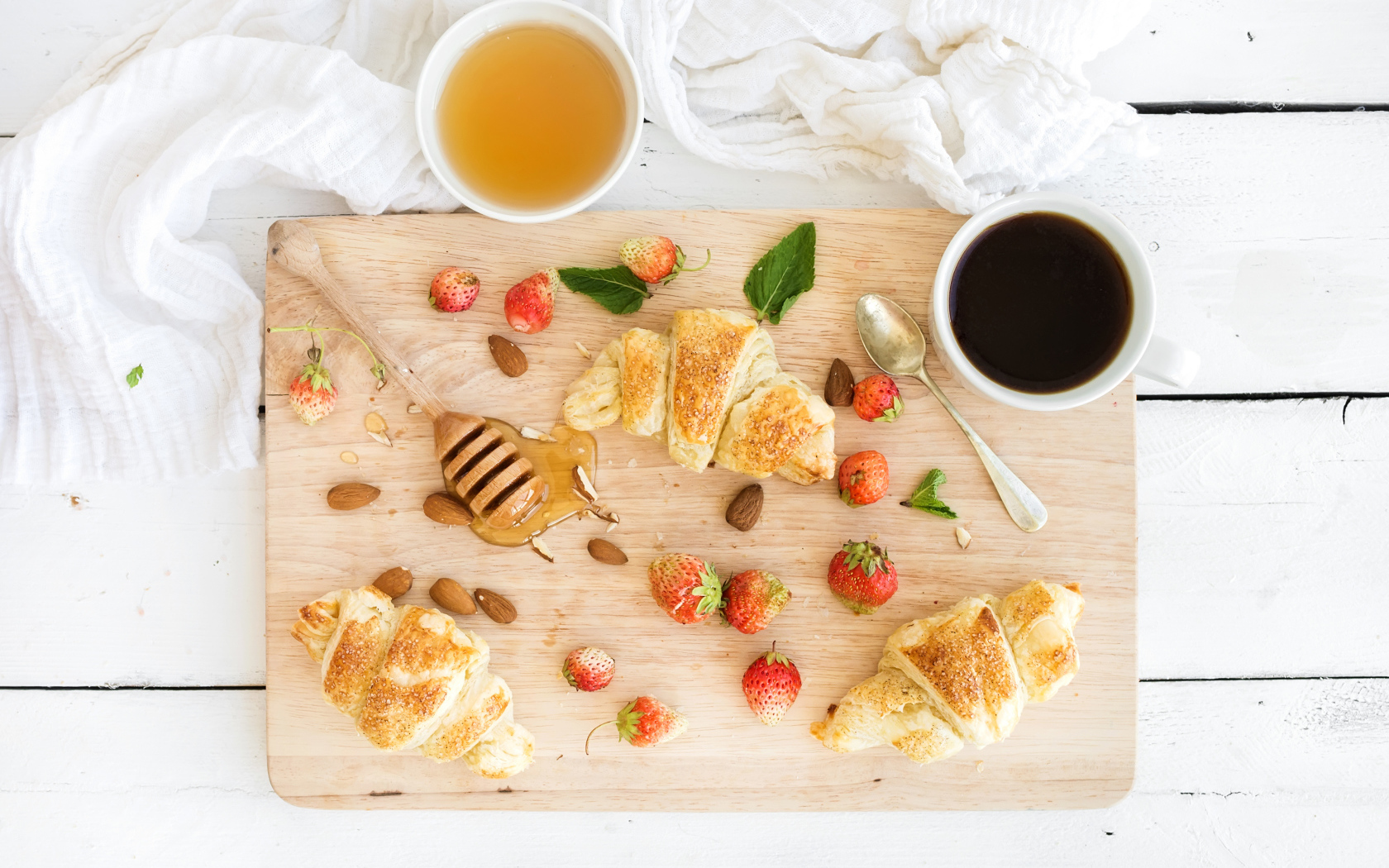 Круассаны, мед, свежие ягоды клубники и кофе на завтрак