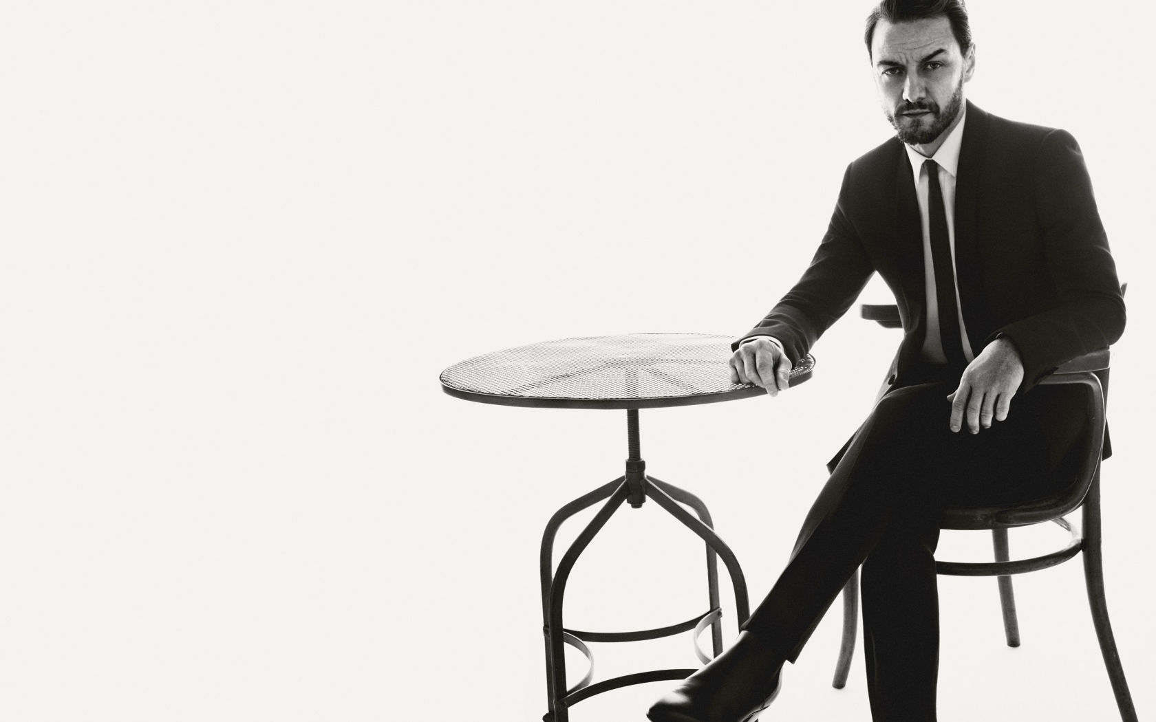 Актер Джеймс Макэвой сидит на стуле за столом черно-белое фото