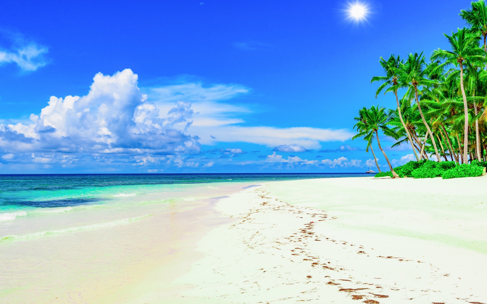 Следы на белом песке на тропическом пляже под красивым голубым небом
