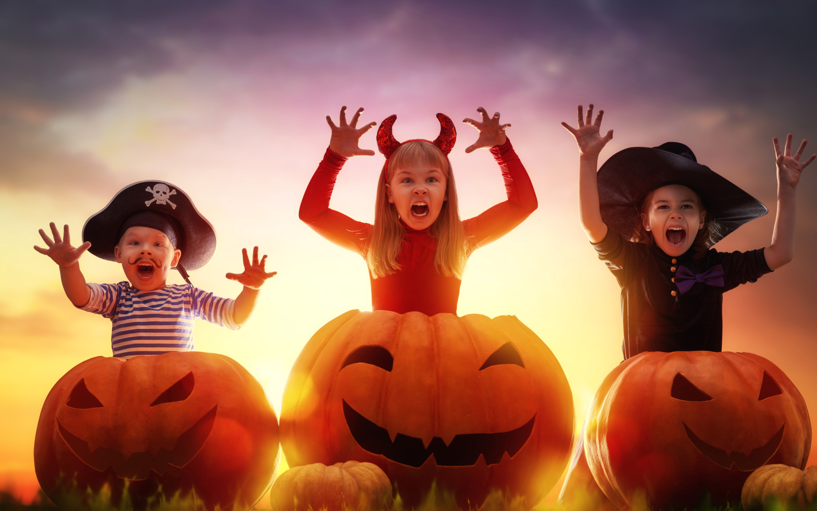 Маленькие дети в костюмах на Хэллоуин с большими тыквами