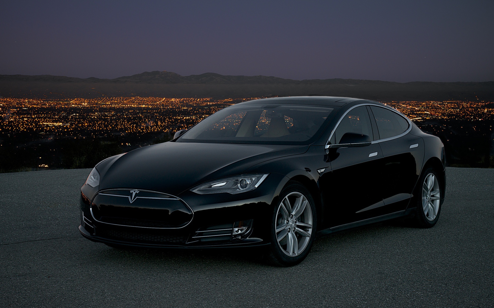 Черный стильный электромобиль Tesla Model S на фоне ночного мегаполиса 