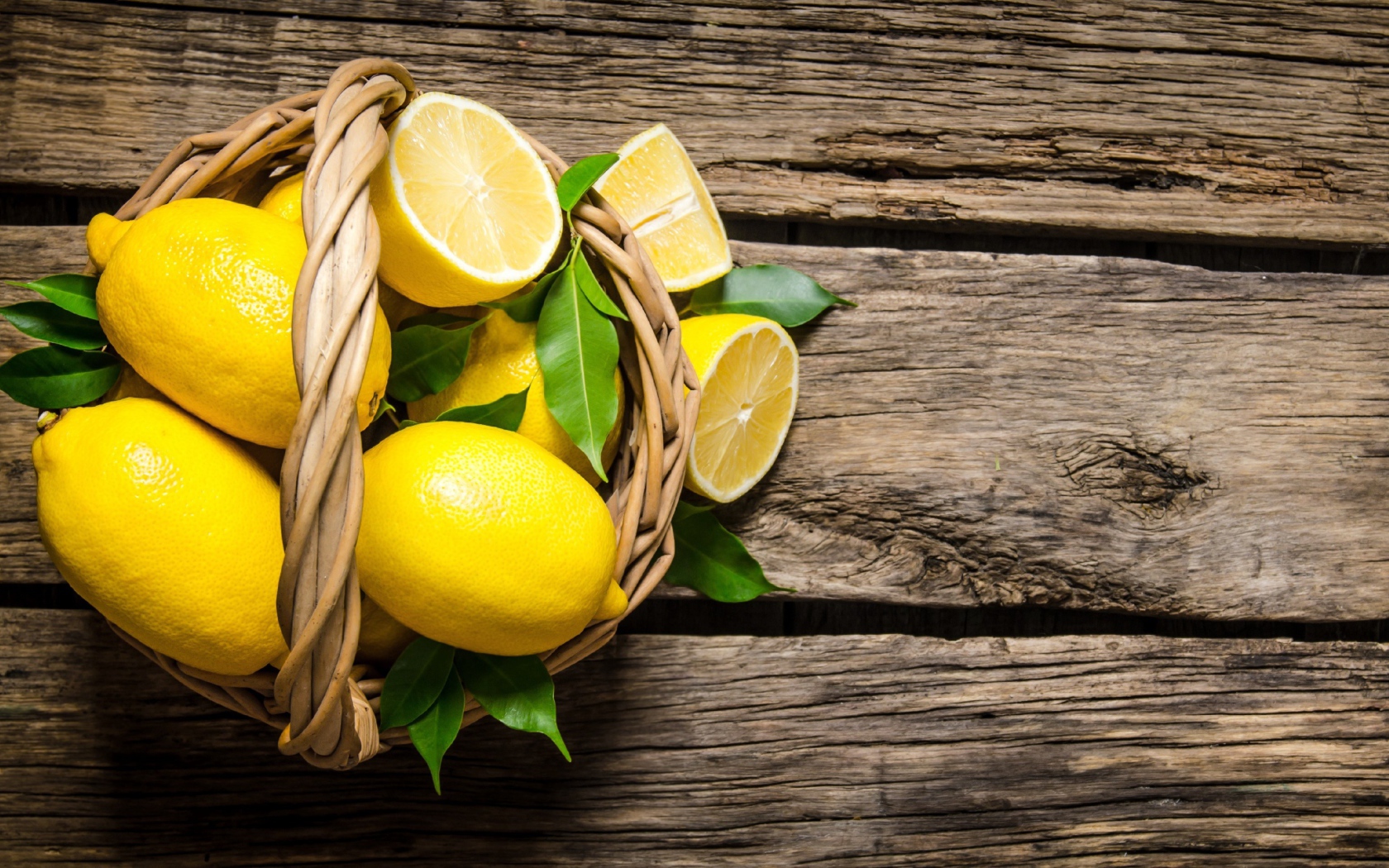 Красивые желтые лимоны в корзине на деревянном столе