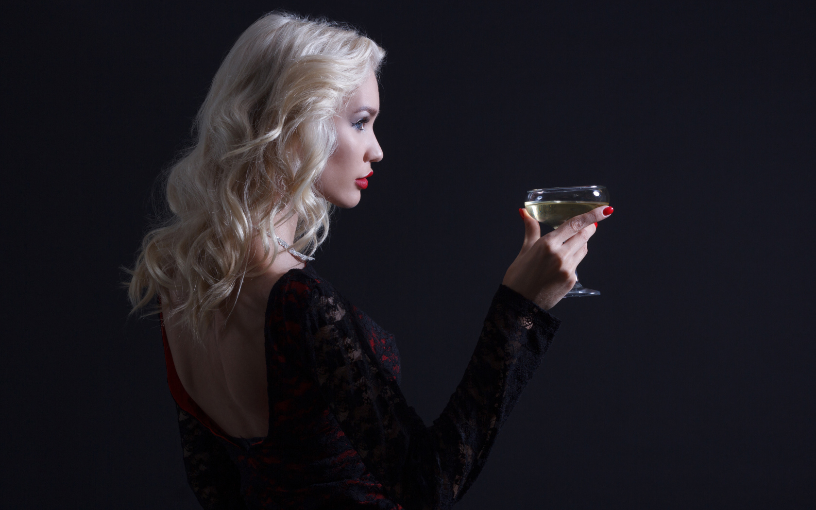 Блондинка с бокалом мартини в руках сером фоне 