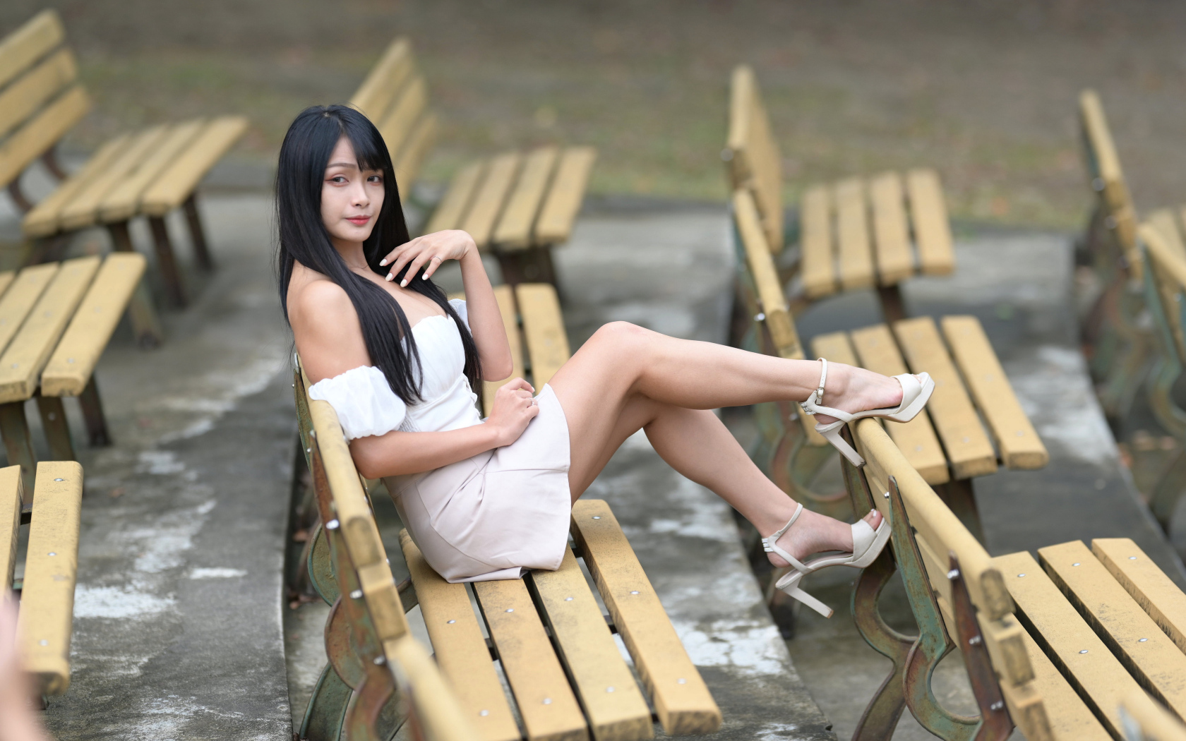 Длинноволосая азиатка сидит на деревянной лавке
