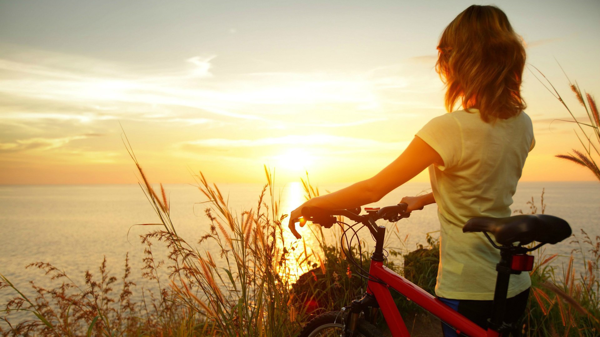 Девушка с велосипедом смотрит на закат