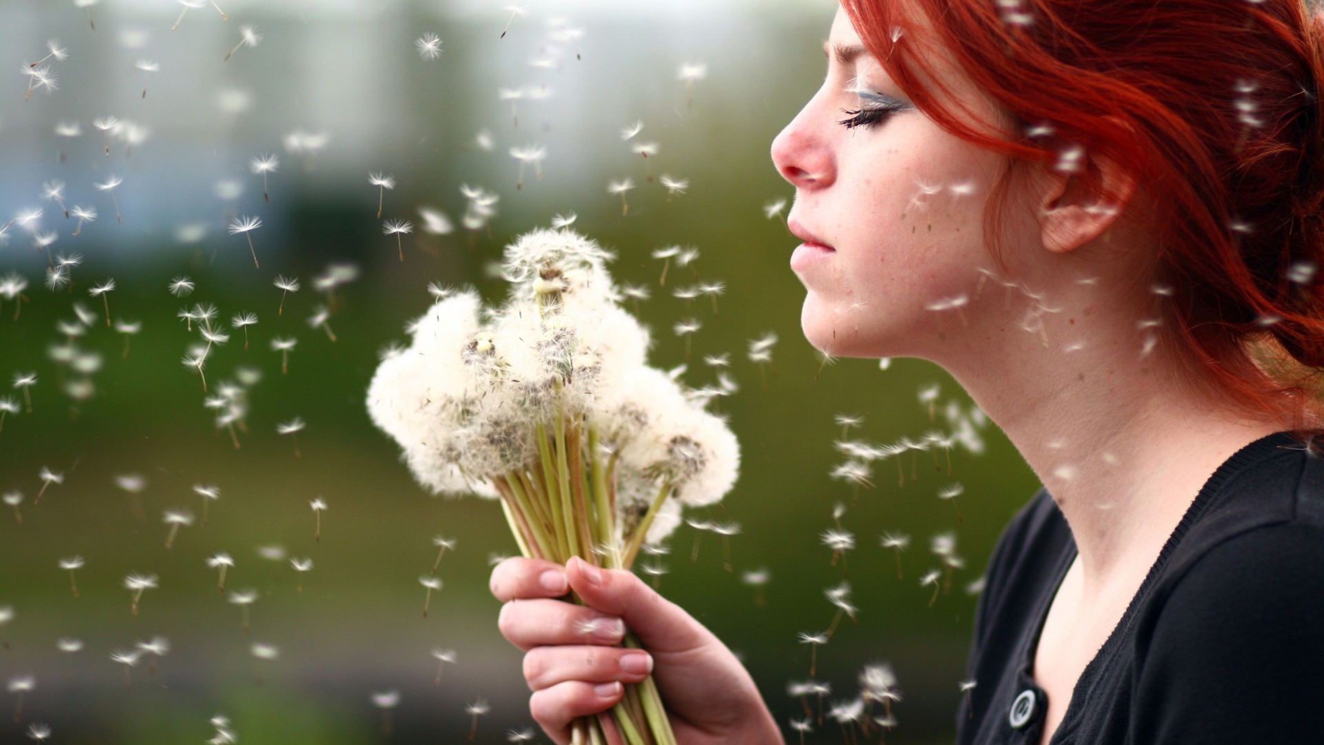 Red-haired girl with a bouquet of mature dandelions