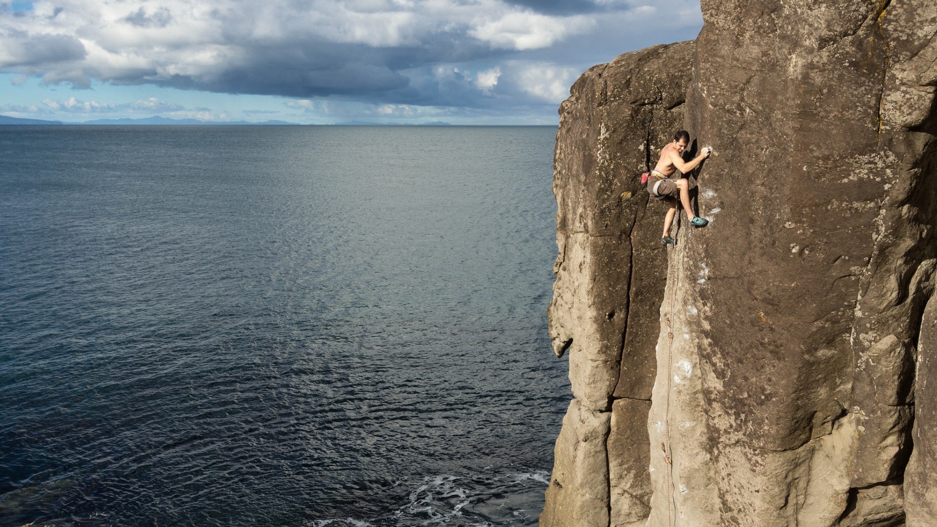 Male rock climber on a cliff above the sea