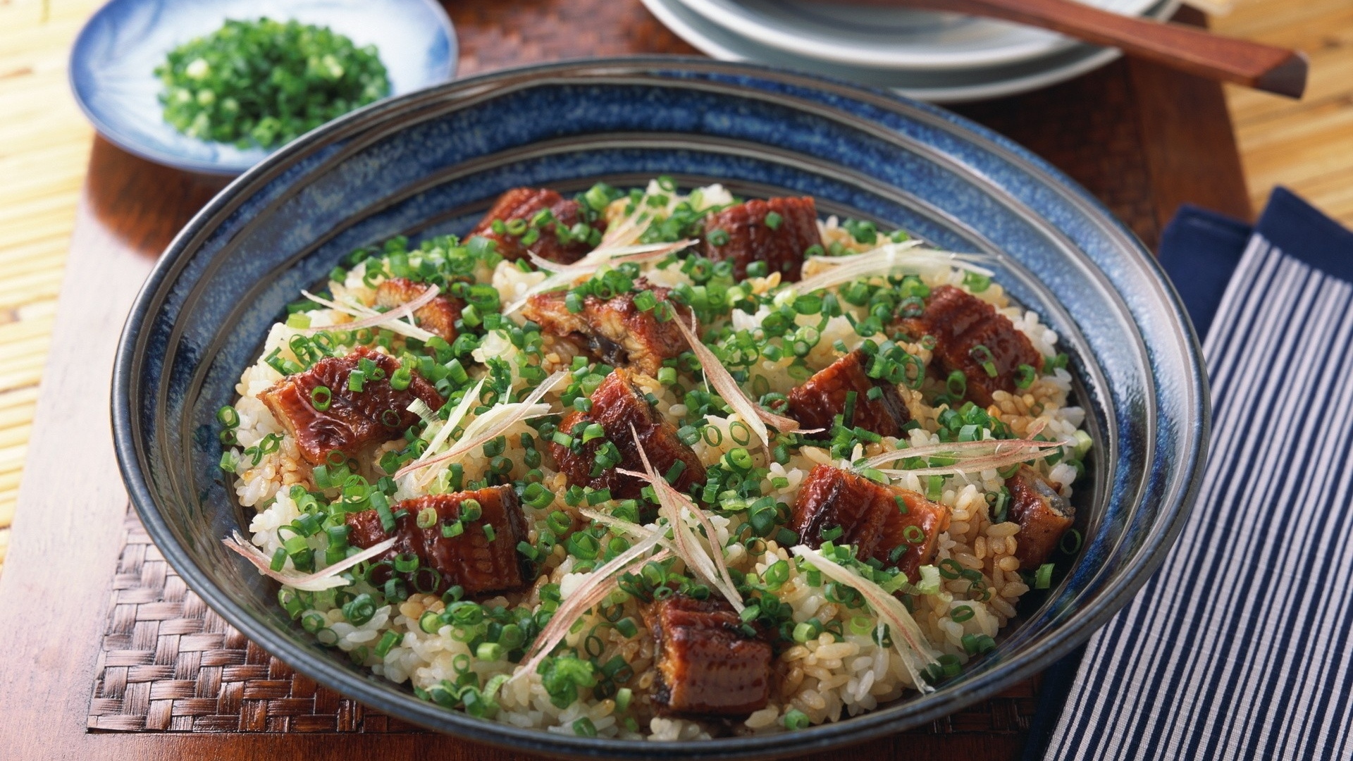 Рисовый плов с кусочками мяса и зеленым луком на столе