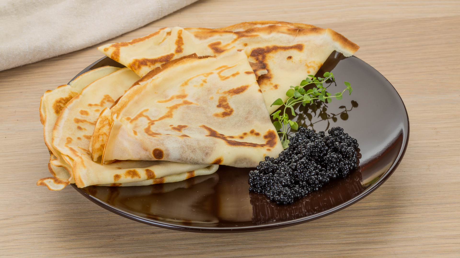 Thin pancakes on a plate with black caviar