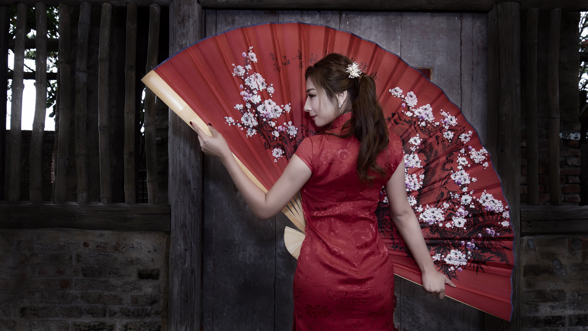 Красивая девушка азиатка в красном платье с большим веером
