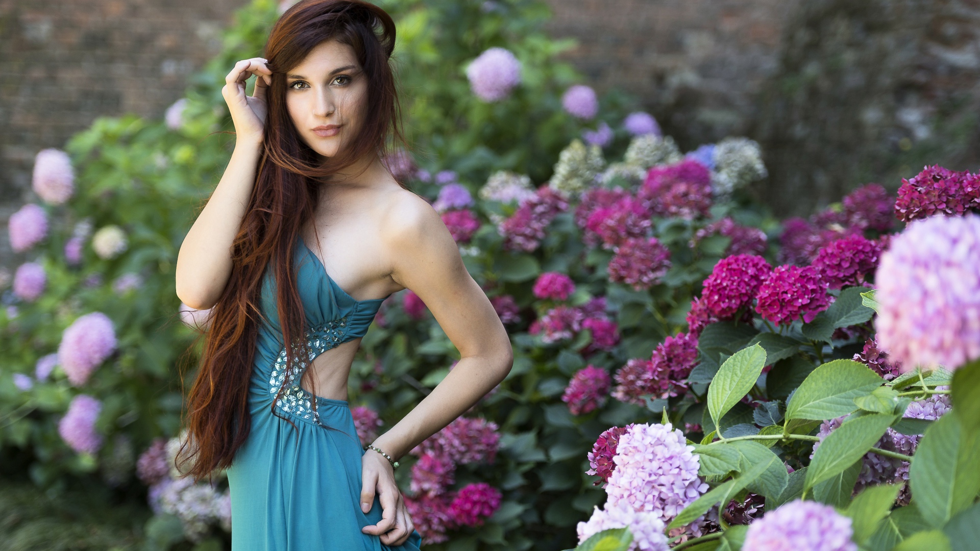 Красивая девушка модель в зеленом платье рядом с цветами гортензии