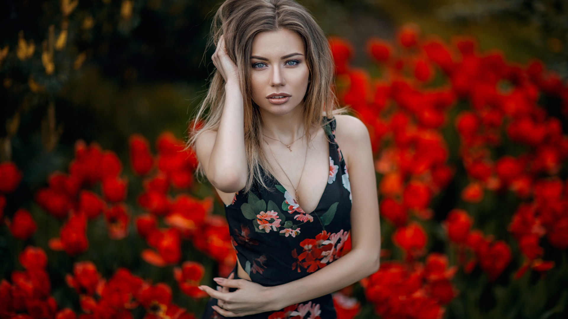 Красивая молодая девушка позирует на фоне красных тюльпанов