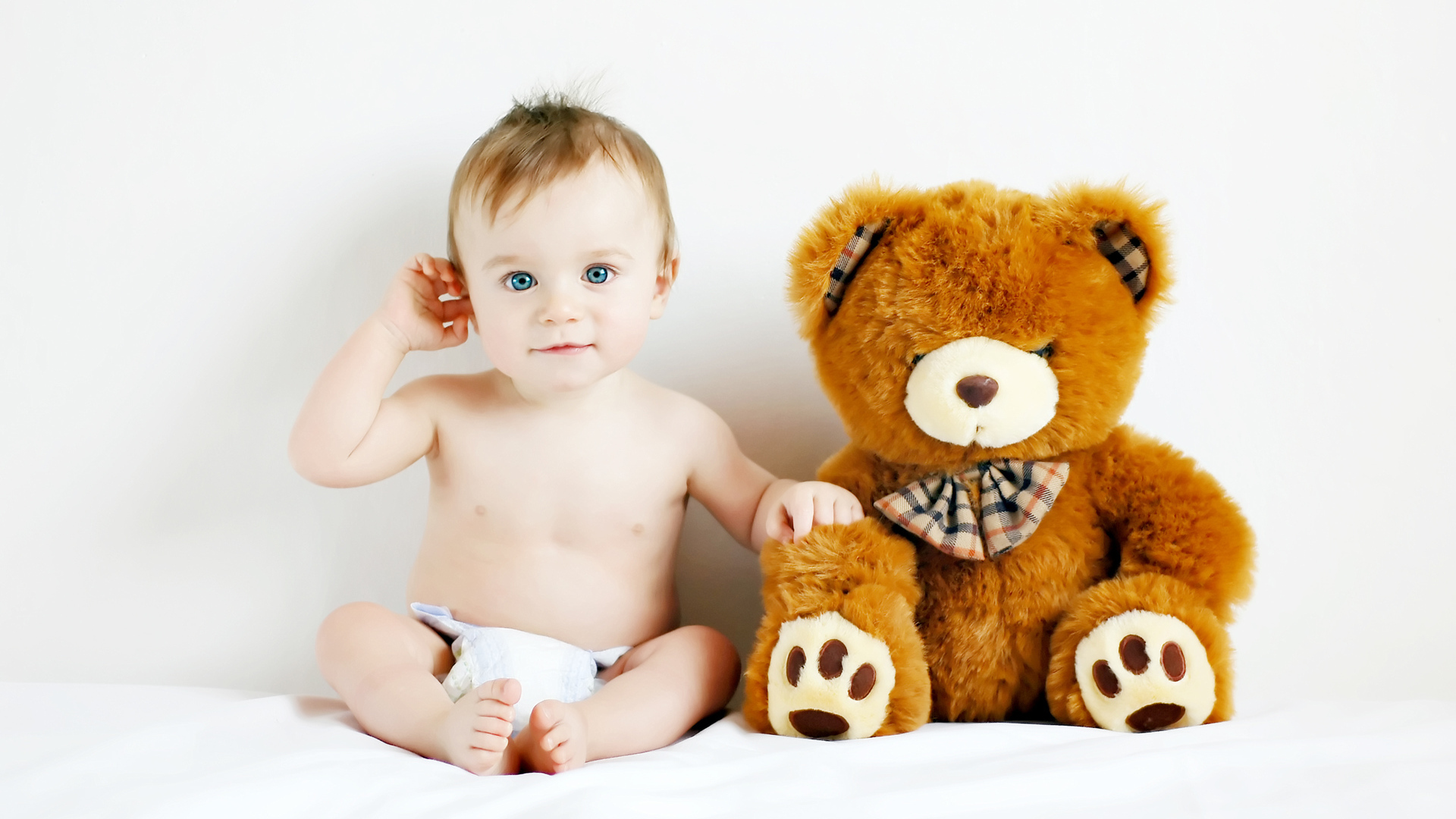 Маленький голубоглазый ребенок с большим плюшевым медведем