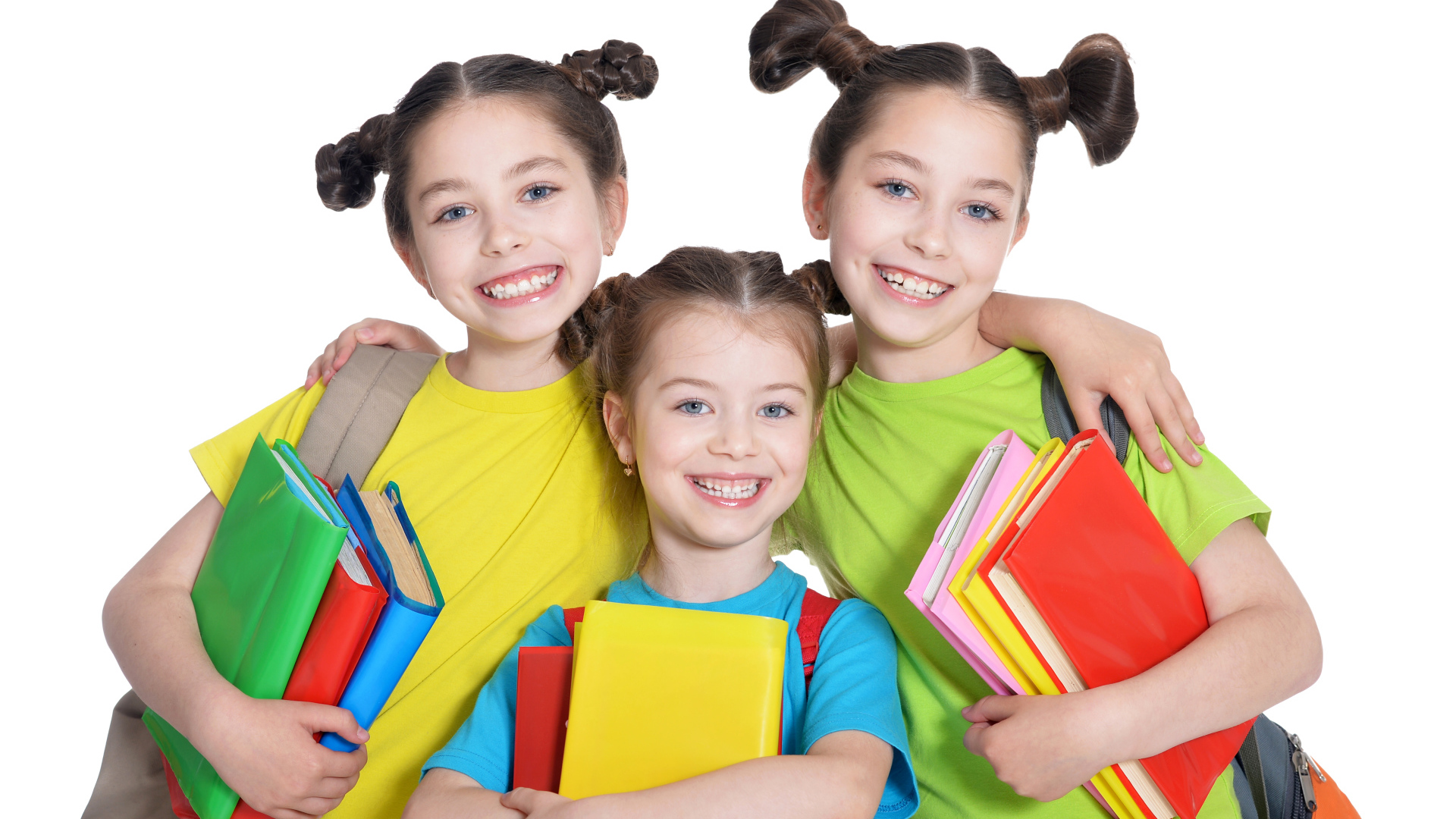 Три маленькие улыбающиеся девочки с книгами на белом фоне