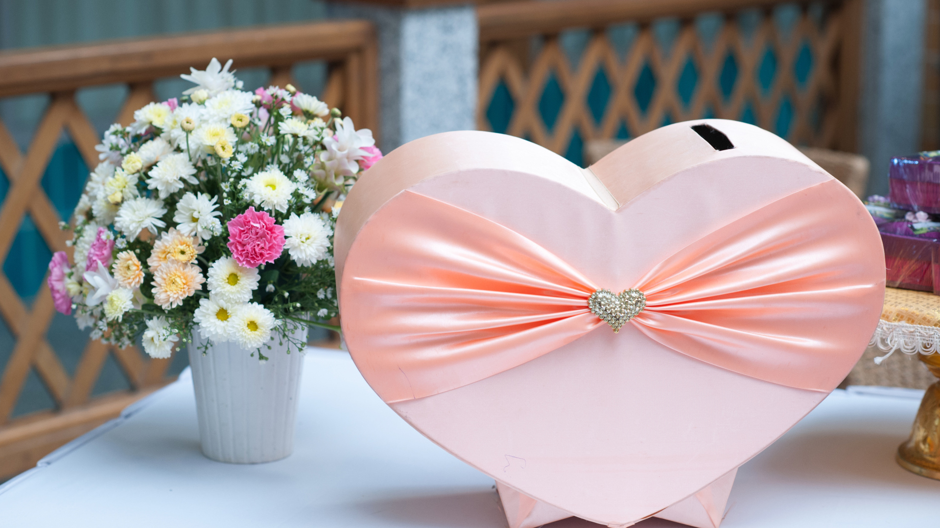 Большая розовая коробка в форме сердца на столе с букетом хризантем