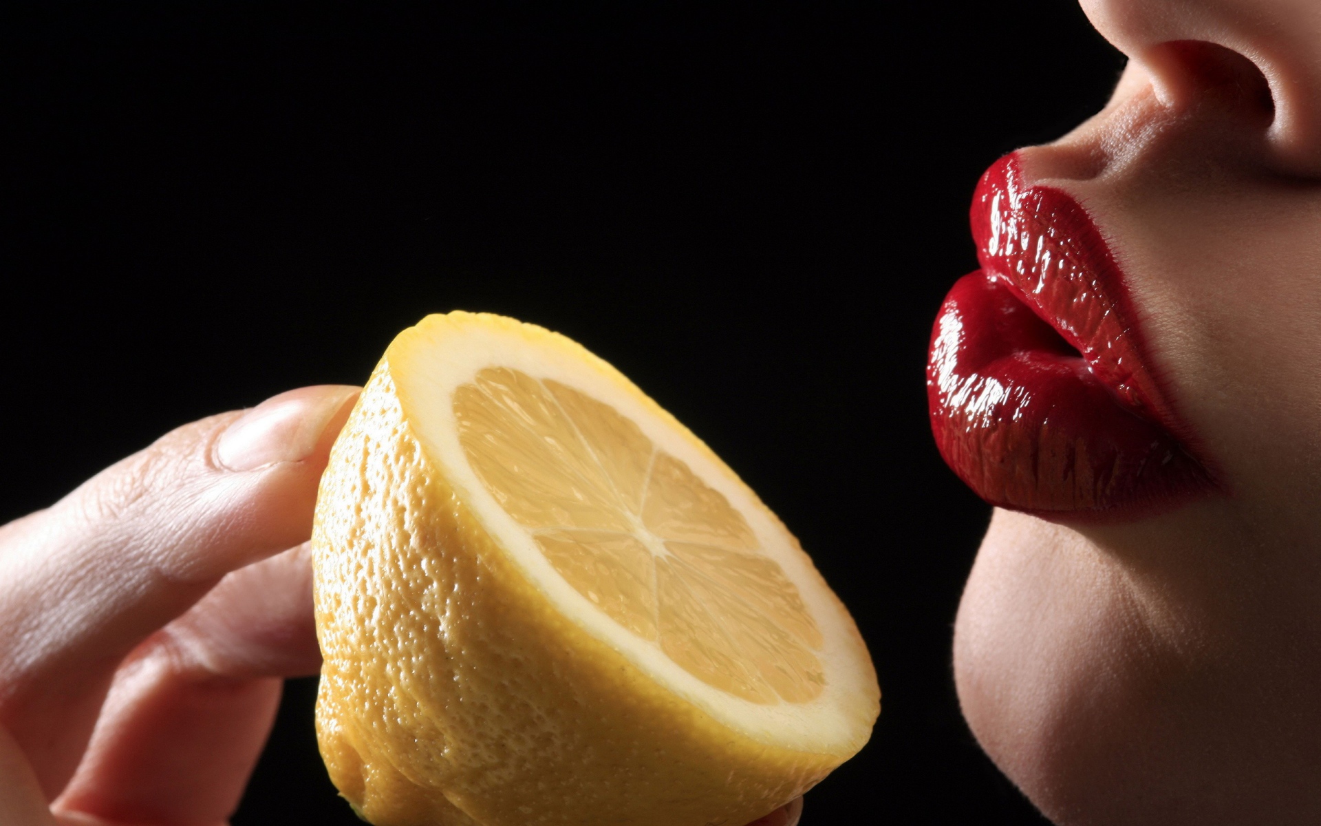 Девушка поднесла лимон к губам
