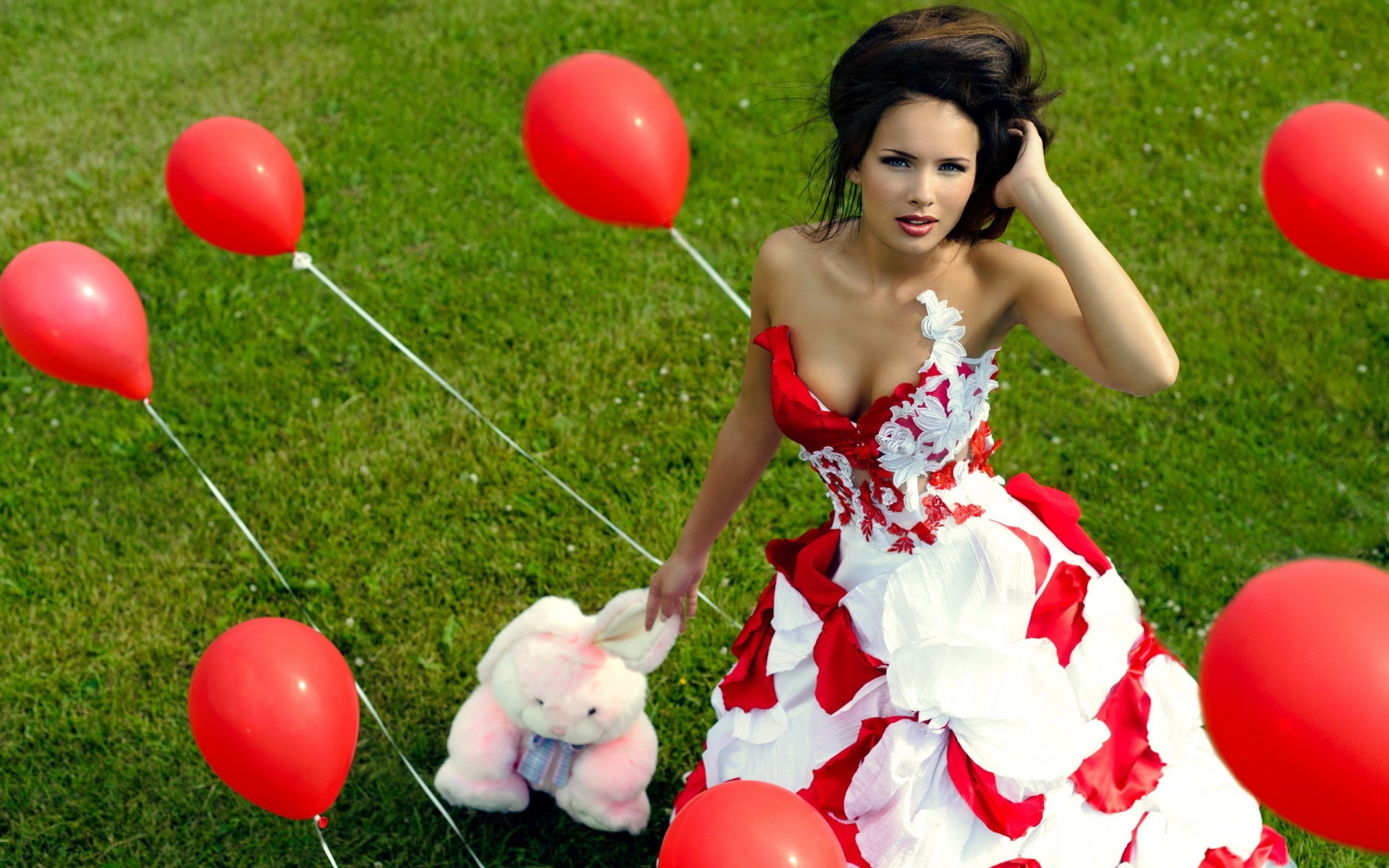 Девушка с игрушкой среди красных воздушных шариков