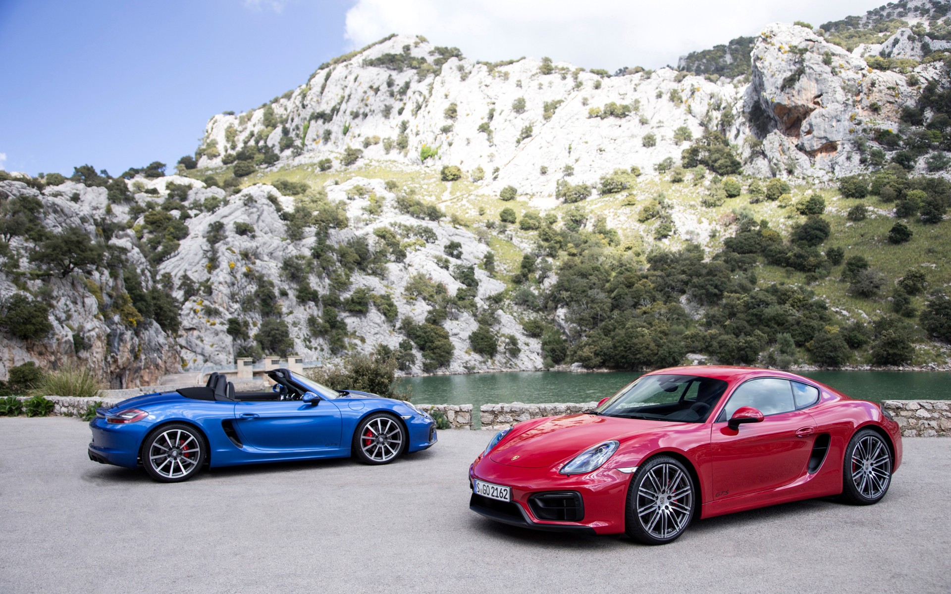Два спортивных автомобиля Porsche Boxster и Porsche Cayman GTS  у воды 