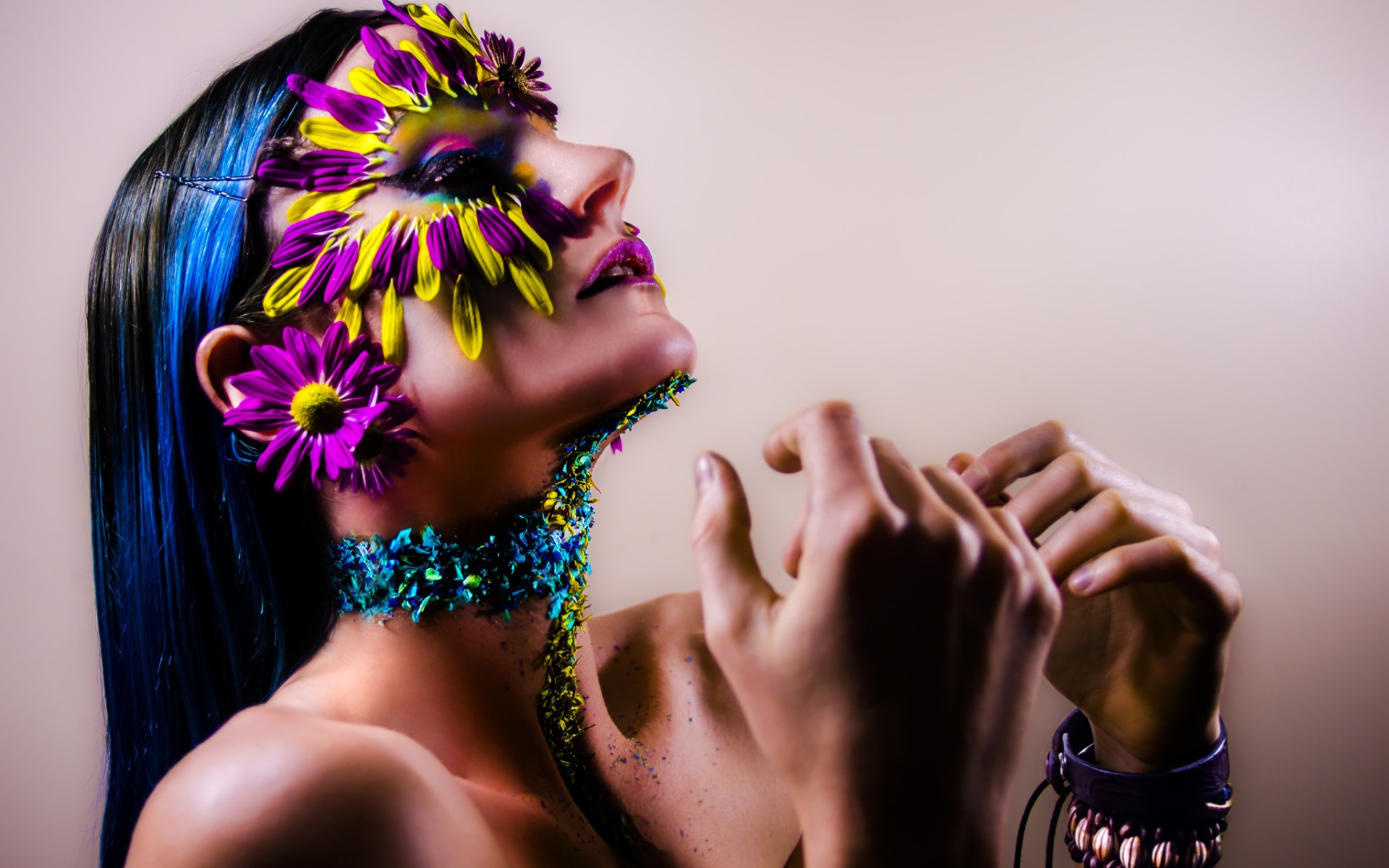 Девушка с украшенным лепестками цветов лицом и ярким макияжем