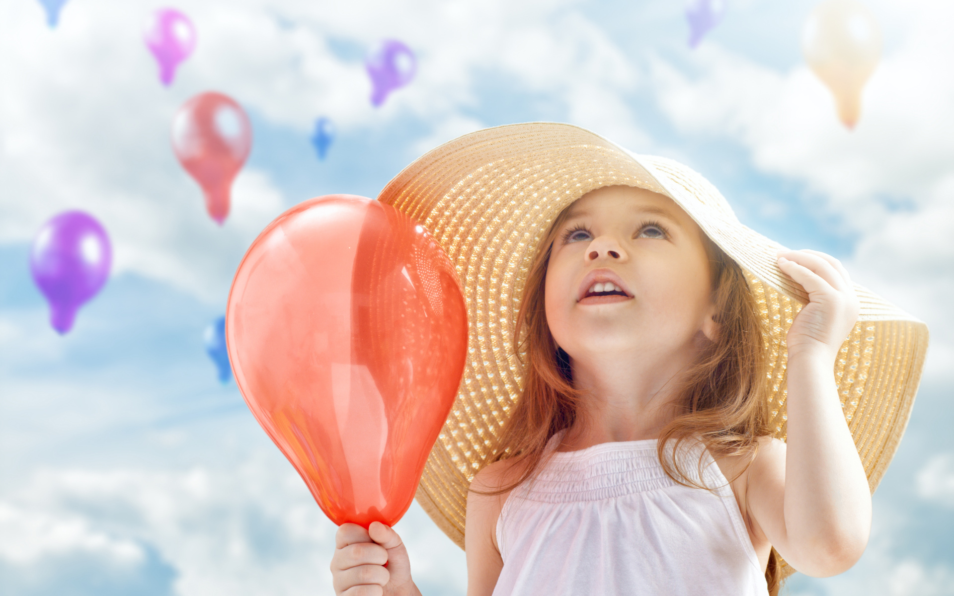 Милая маленькая девочка в большой шляпе с воздушным шариком в руке