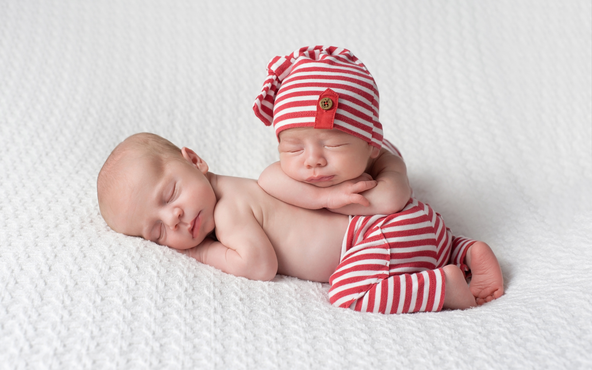 Два милых спящих младенца в полосатых костюмах