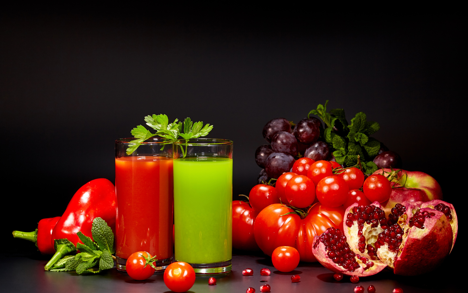 Два стакана сока на столе со свежими помидорами, перцем, гранатом, виноградом и зеленью