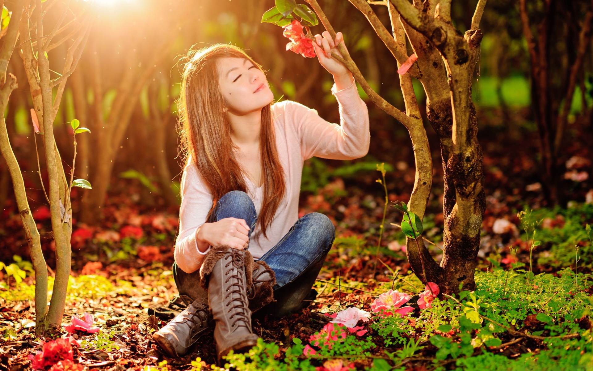 Девушка сидит на земле под ярким солнцем в лесу