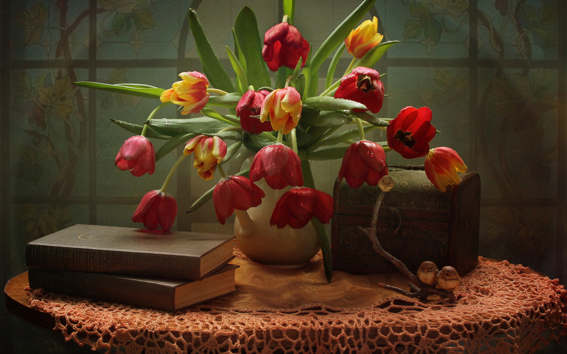 A bouquet of tulips on a table with books and a box