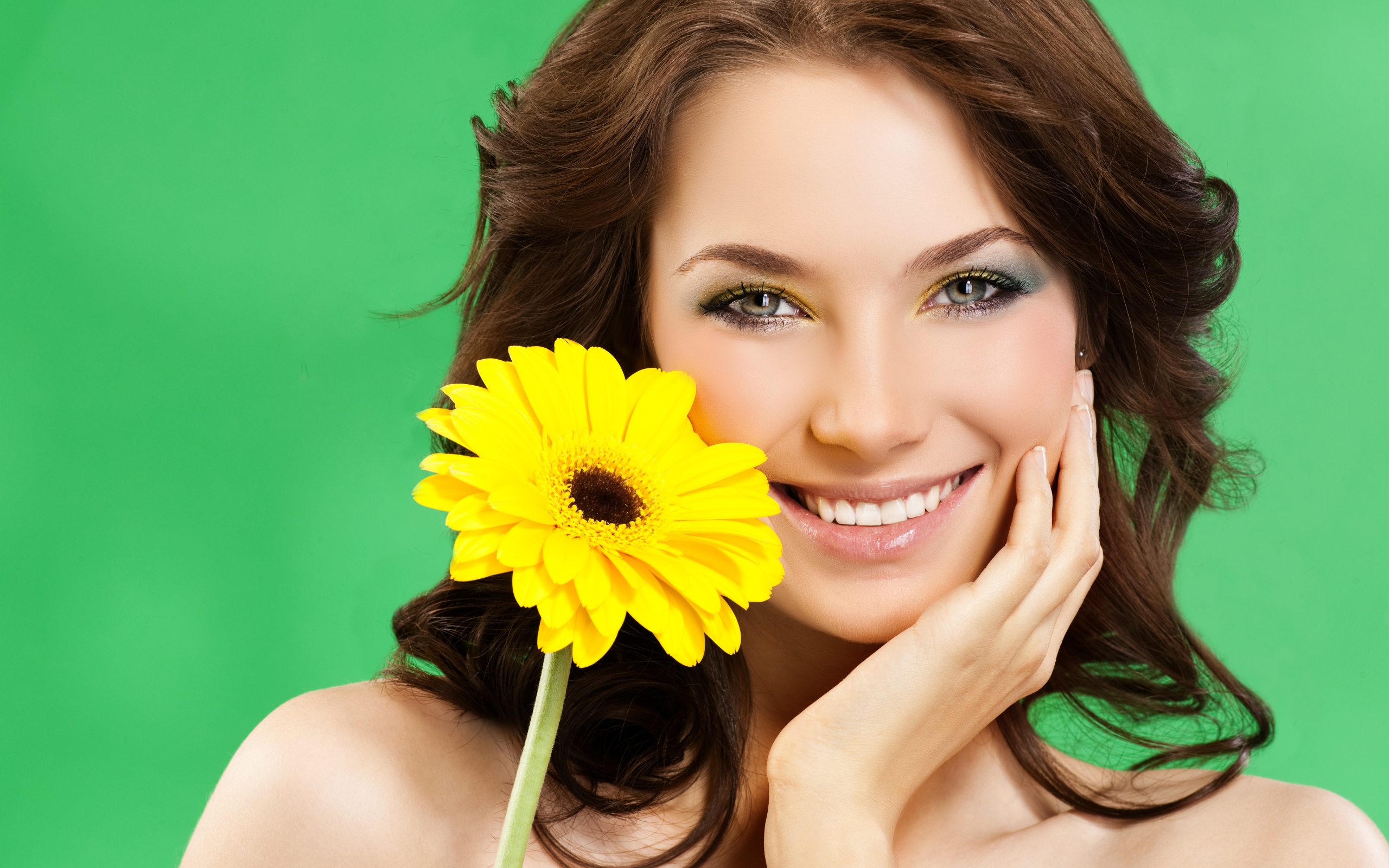 Девушка с красивой улыбкой и цветком желтой герберы в руках