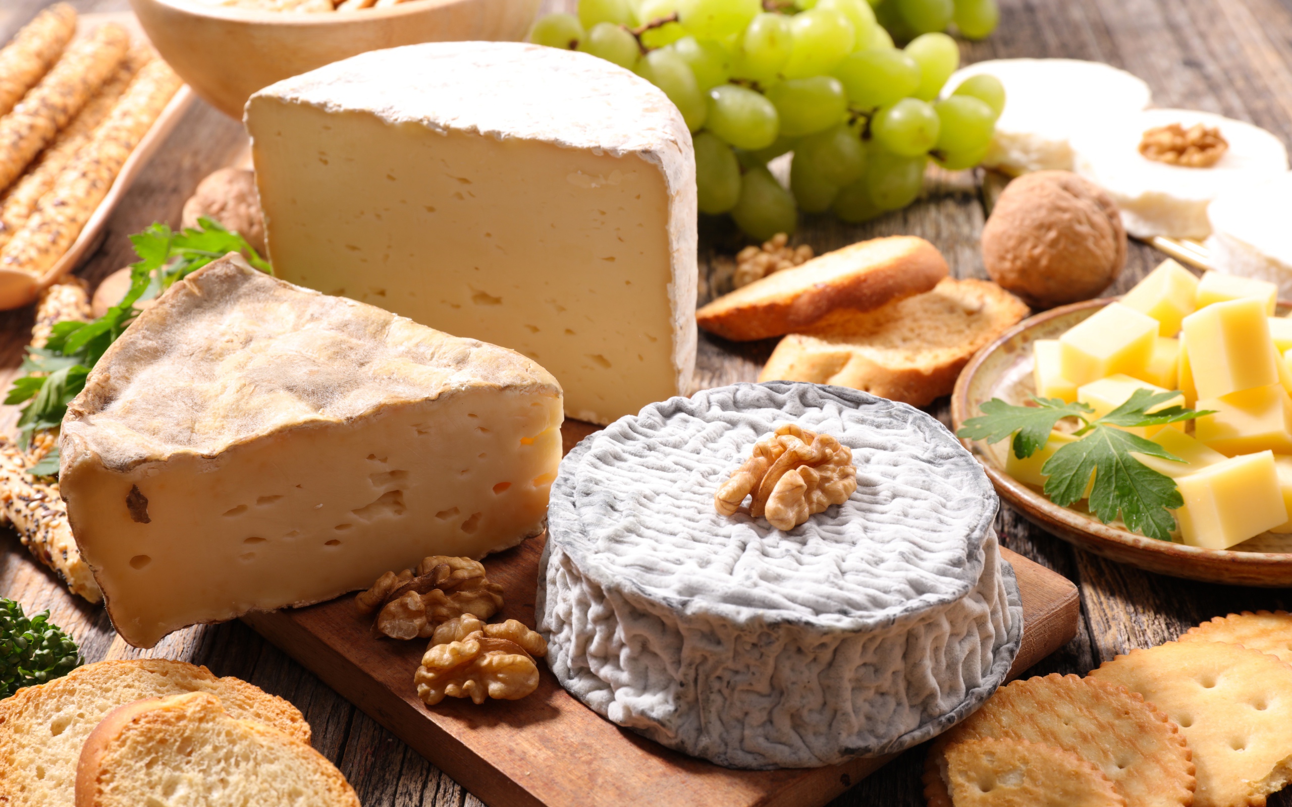 Сыр с плесенью на столе с виноградом, орехами и хлебом