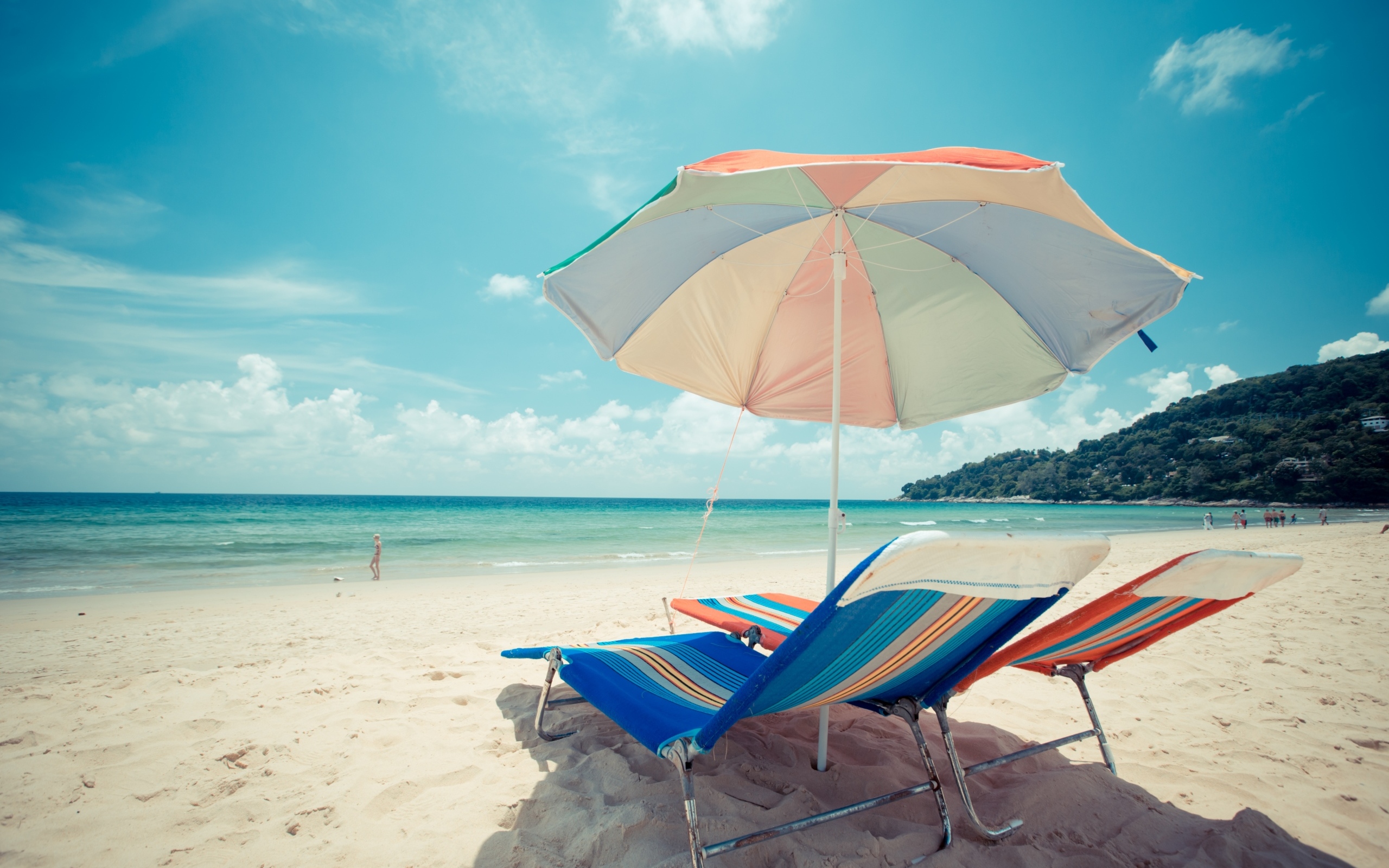 Шезлонги и разноцветный зонт на пляже летом