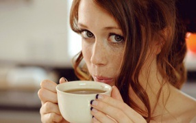 Девушка с веснушками пьет кофе