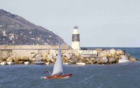 Boat on the background of the lighthouse at the resort Imperia, Italy